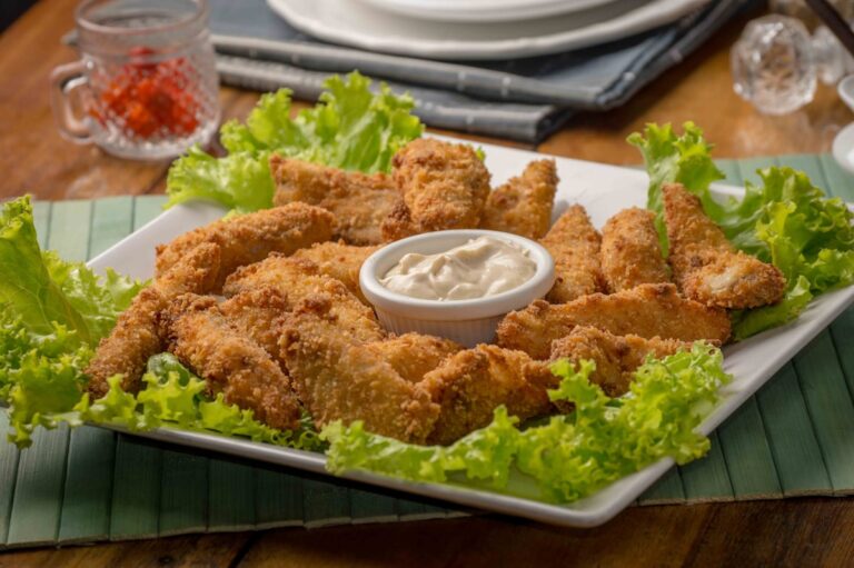 Golden crispy Southern fried chicken pieces on a wooden board with dipping sauce