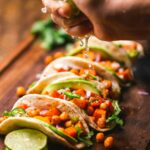 Freshly made classic beef tacos with pico de gallo avocado and cilantro on wooden board