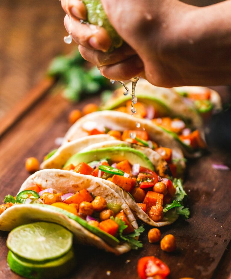 Freshly made classic beef tacos with pico de gallo avocado and cilantro on wooden board